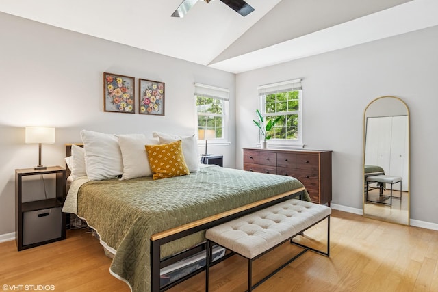 bedroom with baseboards, light wood-style flooring, and vaulted ceiling