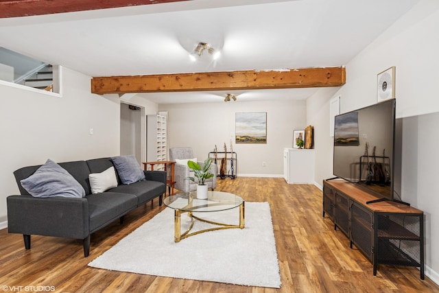 living room with baseboards, beam ceiling, and light wood-type flooring