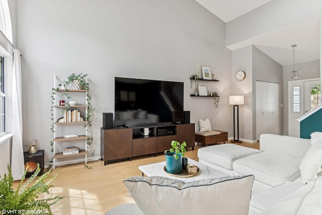 living room with baseboards, high vaulted ceiling, and wood finished floors