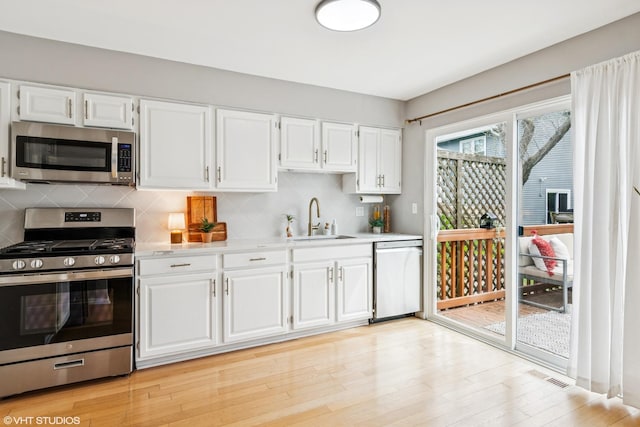 kitchen with a sink, light countertops, stainless steel appliances, white cabinetry, and visible vents