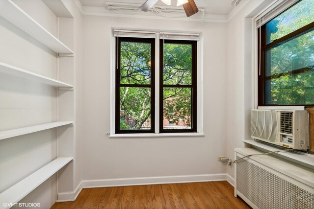 interior space with light wood-style flooring, radiator, ceiling fan, and cooling unit