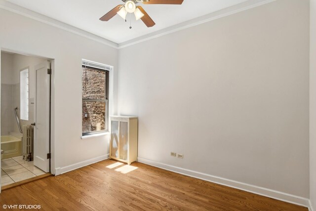 unfurnished bedroom featuring crown molding, baseboards, light wood finished floors, connected bathroom, and radiator heating unit