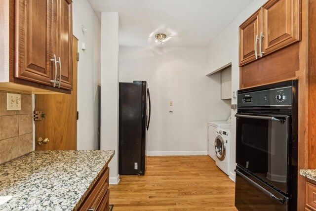 kitchen with brown cabinets, light stone counters, light wood finished floors, and black appliances
