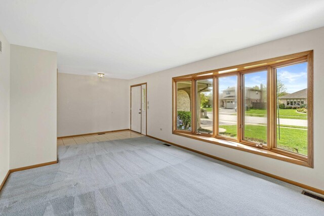 spare room featuring baseboards, visible vents, and light carpet