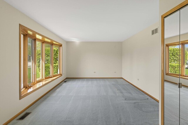 unfurnished room with visible vents, baseboards, and light colored carpet