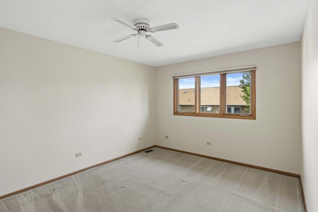 spare room with baseboards, ceiling fan, light carpet, and visible vents