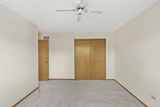 unfurnished bedroom featuring light colored carpet, baseboards, visible vents, and a closet