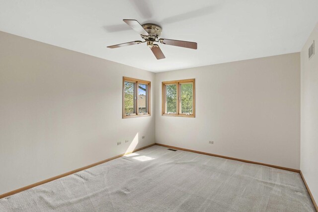 empty room featuring a ceiling fan, baseboards, visible vents, and light carpet