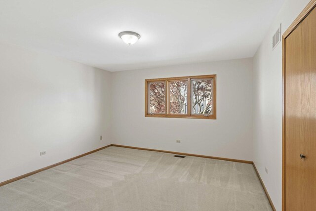 empty room featuring baseboards, light colored carpet, and visible vents