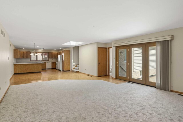 unfurnished living room with visible vents, baseboards, recessed lighting, a chandelier, and a skylight