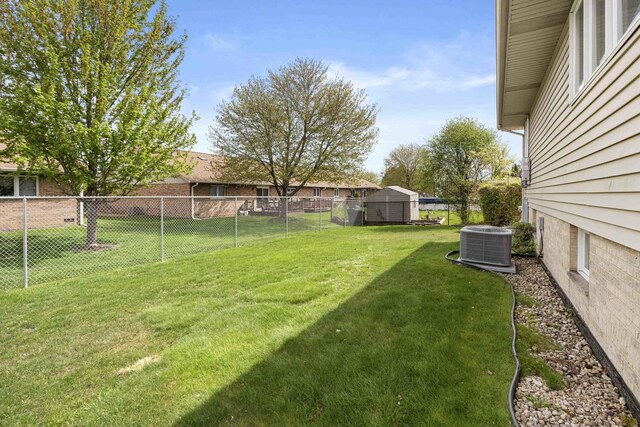 view of yard featuring fence, central AC unit, and a storage unit