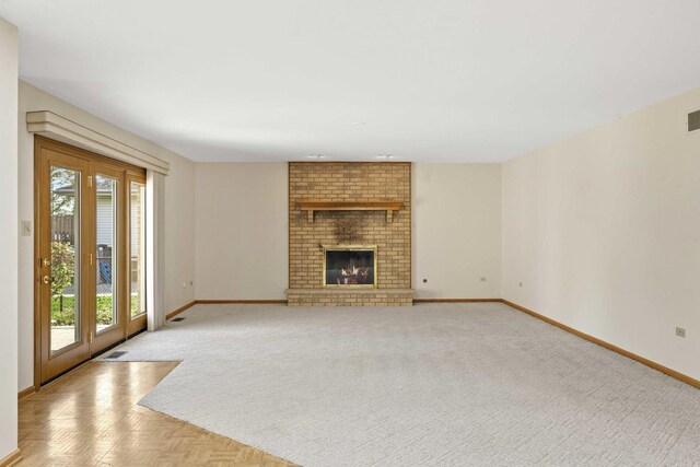 unfurnished living room with baseboards, visible vents, a fireplace, and light colored carpet