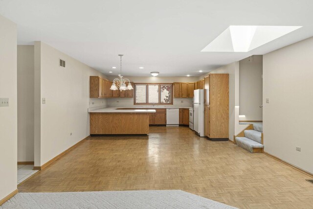 kitchen with brown cabinets, white appliances, a peninsula, baseboards, and visible vents