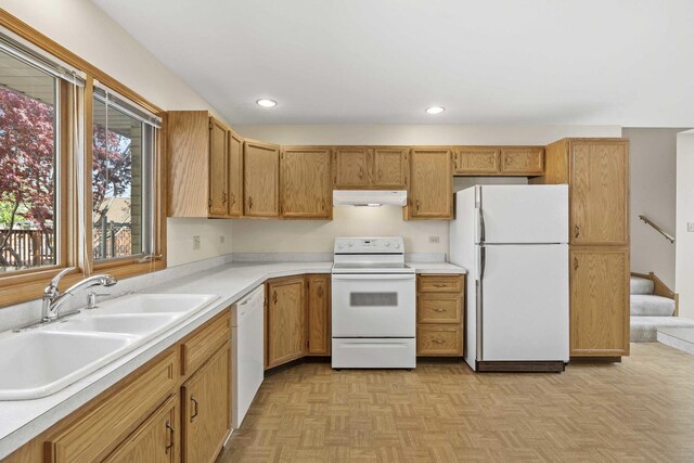 kitchen featuring white appliances, recessed lighting, light countertops, under cabinet range hood, and a sink