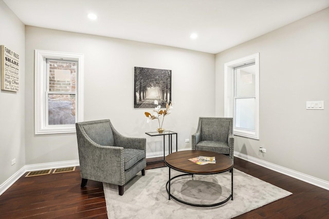 living area with baseboards, wood finished floors, and visible vents