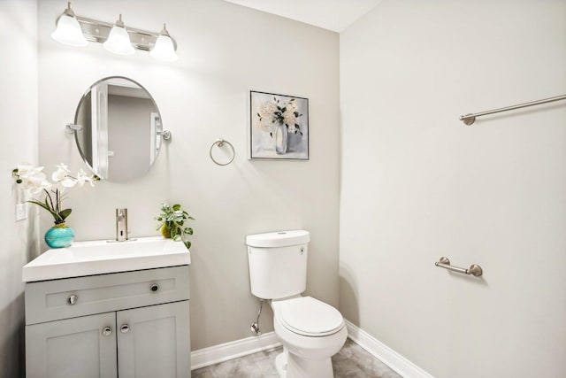 bathroom featuring toilet, baseboards, and vanity