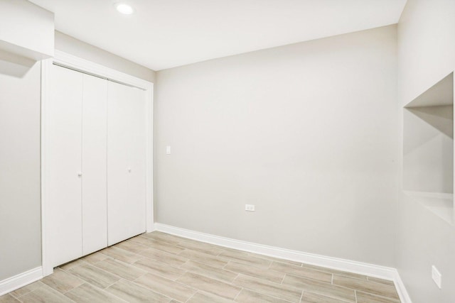 unfurnished bedroom featuring recessed lighting, baseboards, wood tiled floor, and a closet