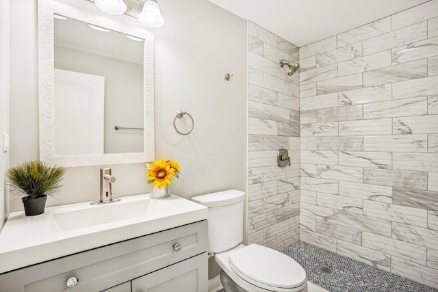 full bathroom with vanity, a tile shower, and toilet
