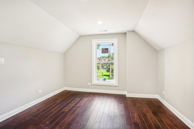 additional living space featuring baseboards, vaulted ceiling, and dark wood-type flooring