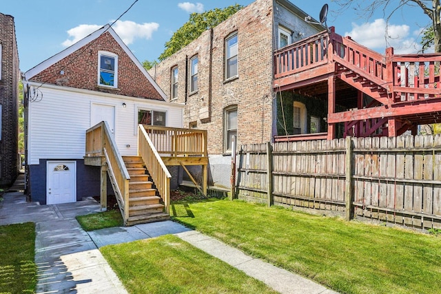 rear view of house featuring fence, a lawn, a deck, and stairway