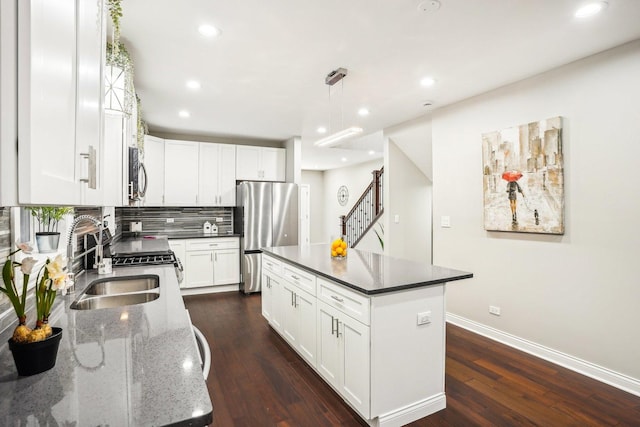 kitchen featuring appliances with stainless steel finishes, a sink, recessed lighting, baseboards, and dark wood-type flooring