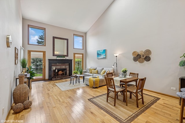 15733 Liberty Ct, Orland Park, IL 60462 - living room featuring baseboards, a warm lit fireplace, light wood-style flooring, and high vaulted ceiling