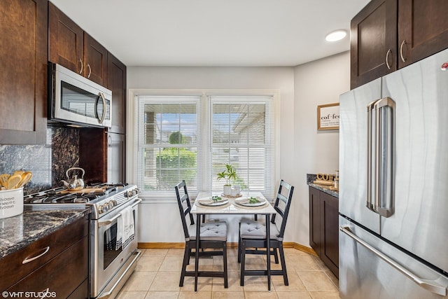 15733 Liberty Ct, Orland Park, IL 60462 - kitchen with stainless steel appliances, dark brown cabinetry, decorative backsplash, baseboards, and dark stone counters