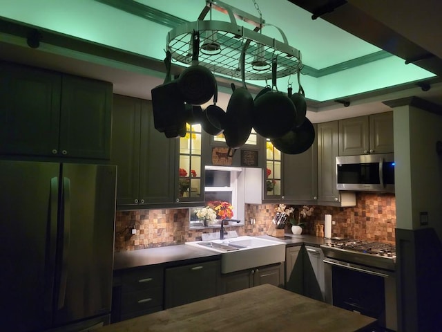 kitchen featuring stainless steel appliances, a sink, decorative backsplash, and dark countertops