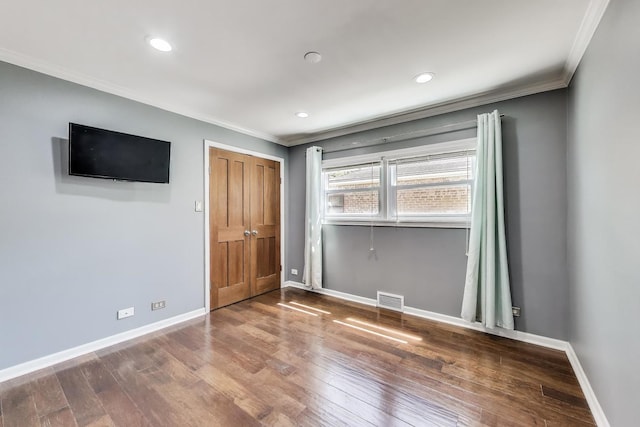 empty room with crown molding, baseboards, wood finished floors, and recessed lighting