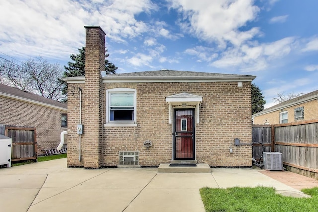 view of front facade with fence, cooling unit, brick siding, and a patio area