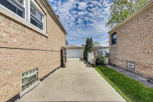 view of side of home featuring brick siding, a garage, an outbuilding, and fence