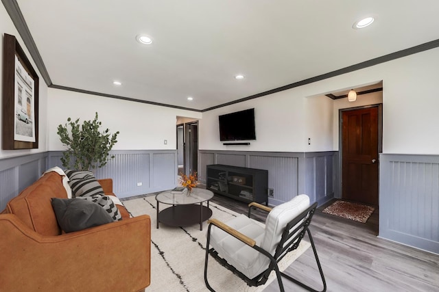 living area featuring ornamental molding, wainscoting, light wood-style floors, recessed lighting, and a fireplace