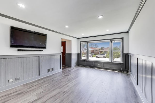 unfurnished living room featuring ornamental molding, wood finished floors, wainscoting, and recessed lighting