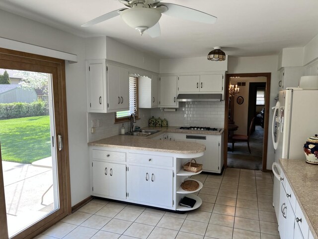 kitchen featuring decorative backsplash, gas stovetop, a sink, light countertops, and under cabinet range hood