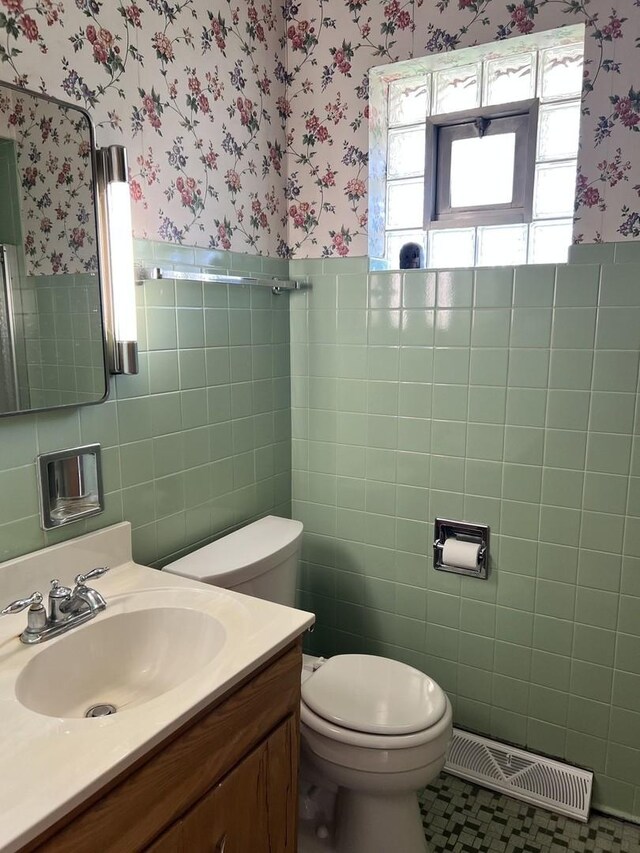 bathroom with visible vents, tile walls, toilet, and wallpapered walls