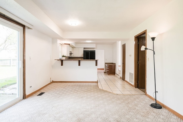 unfurnished living room with baseboards, light carpet, and visible vents