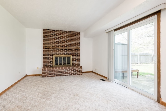 unfurnished living room with a brick fireplace, baseboards, and carpet
