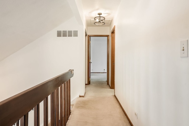 hallway with light colored carpet, baseboards, visible vents, and an upstairs landing