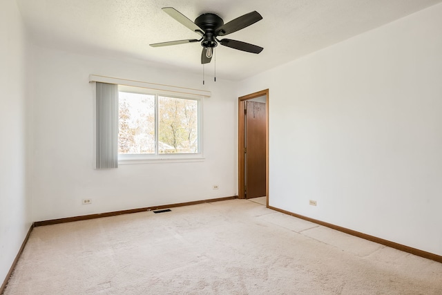 spare room with baseboards, ceiling fan, visible vents, and light colored carpet