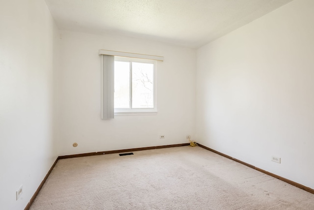 carpeted spare room featuring baseboards and visible vents