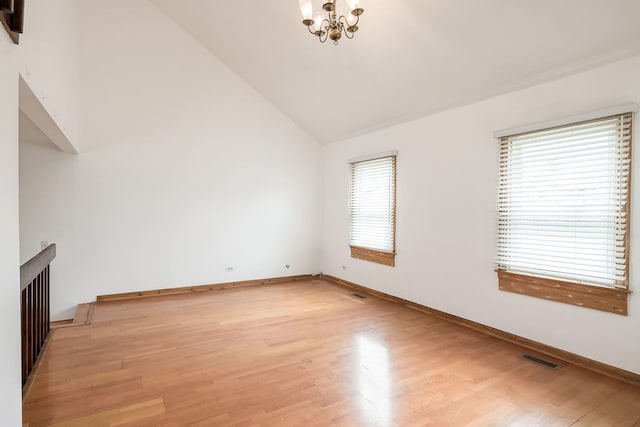 unfurnished living room with a notable chandelier, baseboards, lofted ceiling, light wood-type flooring, and visible vents