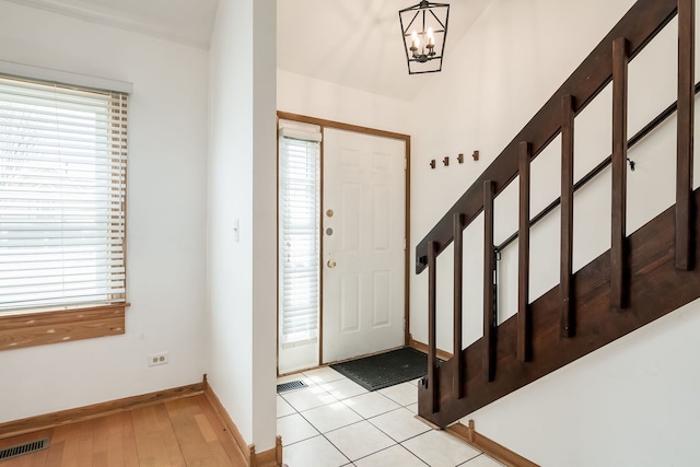 foyer featuring an inviting chandelier, baseboards, plenty of natural light, and visible vents
