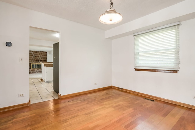 empty room with light wood-style floors, baseboards, and visible vents