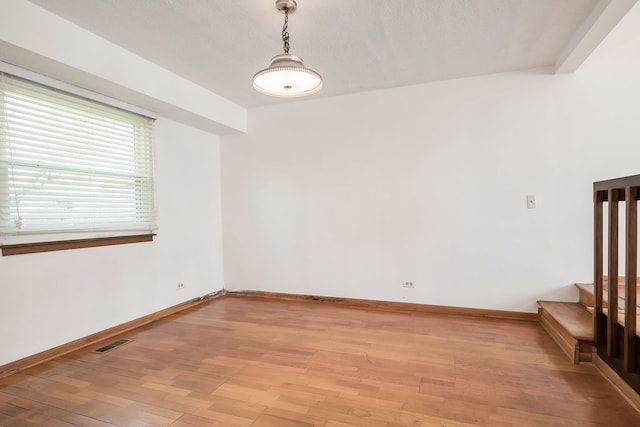 unfurnished room featuring visible vents, light wood-style floors, baseboards, and stairway