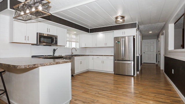 17594 N 2500 E Rd, Towanda, IL 61776 - kitchen with stainless steel appliances, a peninsula, white cabinets, light wood-type flooring, and a kitchen bar