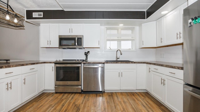 17594 N 2500 E Rd, Towanda, IL 61776 - kitchen with appliances with stainless steel finishes, light wood finished floors, white cabinetry, and decorative light fixtures