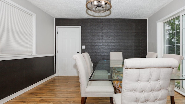 17594 N 2500 E Rd, Towanda, IL 61776 - dining space featuring wood finished floors, a textured ceiling, brick wall, and a chandelier