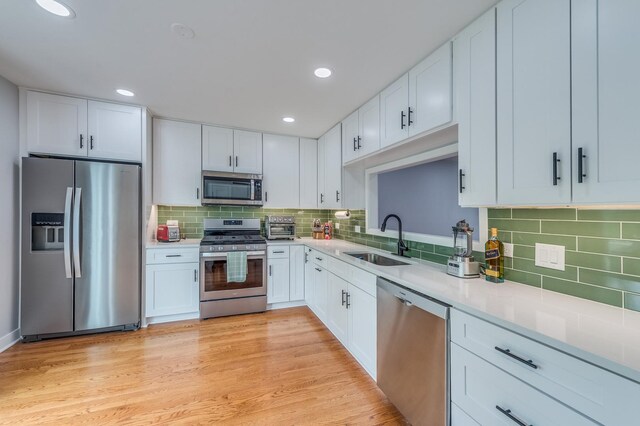 kitchen featuring a sink, light countertops, stainless steel appliances, white cabinetry, and decorative backsplash
