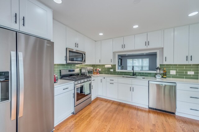 kitchen with a sink, decorative backsplash, appliances with stainless steel finishes, and light countertops