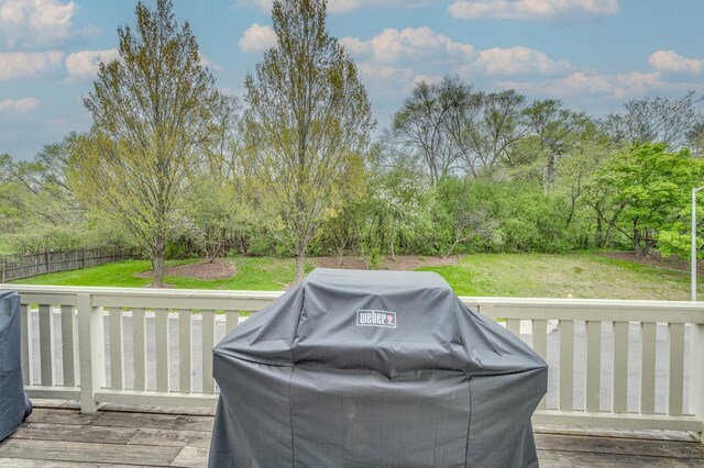 wooden deck featuring a yard, fence, and a grill